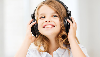 Image showing smiling little girl with headphones at home