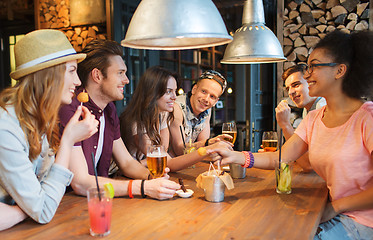 Image showing happy friends with drinks talking at bar or pub