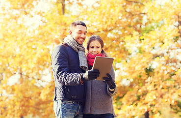 Image showing smiling couple with tablet pc in autumn park