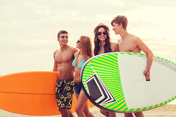 Image showing smiling friends in sunglasses with surfs on beach