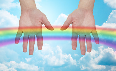 Image showing palms of human hands thumbs up over rainbow in sky