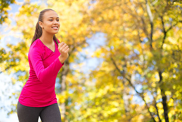 Image showing smiling woman running outdoors at autumn