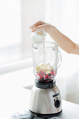 Image showing close up of woman hand pouring milk to blender