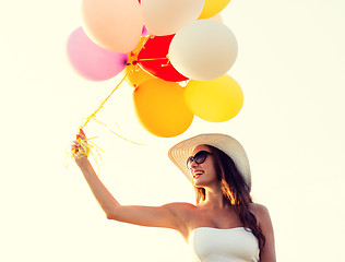 Image showing smiling young woman in sunglasses with balloons