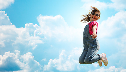 Image showing happy little girl jumping high over blue sky