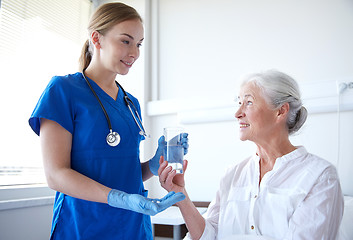 Image showing nurse giving medicine to senior woman at hospital