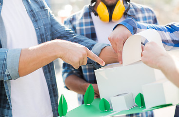 Image showing close up of builders with paper house model