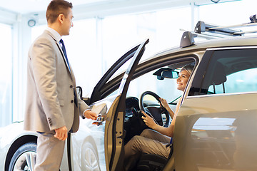 Image showing happy woman with car dealer in auto show or salon