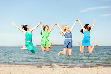 Image showing smiling girls jumping on the beach