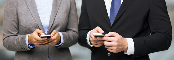 Image showing businessman and businesswoman with smartphones