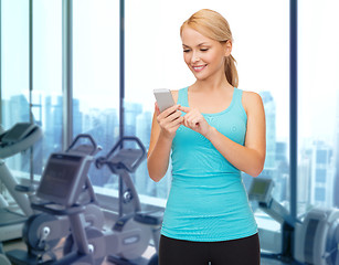 Image showing smiling sporty woman with smartphone in gym