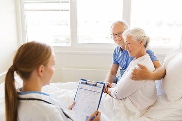 Image showing senior woman and doctor with clipboard at hospital