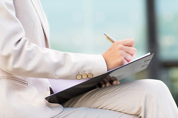 Image showing close up of business woman writing to clipboard