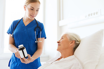 Image showing nurse giving medicine to senior woman at hospital