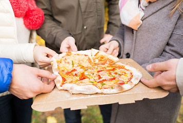 Image showing close up of friends hands eating pizza outdoors