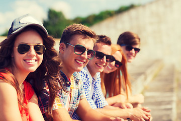 Image showing close up of smiling friends sitting on city street