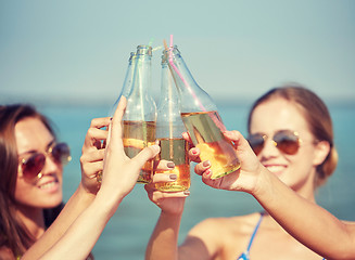 Image showing close up of happy young women with drinks on beach