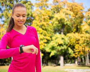 Image showing smiling woman with heart rate watch at autumn park