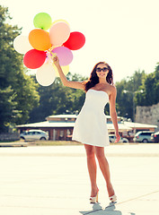 Image showing smiling young woman in sunglasses with balloons