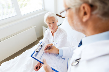 Image showing senior woman and doctor with clipboard at hospital