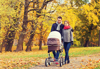 Image showing smiling couple with baby pram in autumn park