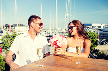 Image showing smiling couple with bunch and champagne at cafe