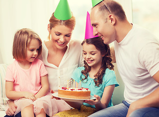 Image showing smiling family with two kids in hats with cake