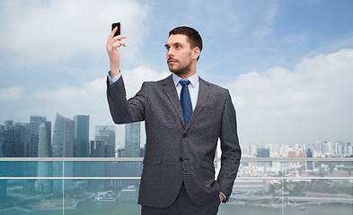 Image showing young businessman with smartphone over city