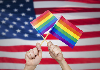 Image showing hands with rainbow flags over american background