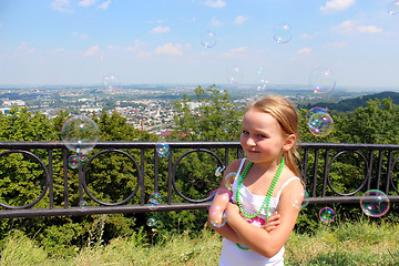 Image showing little girl with soap bubbles out of city