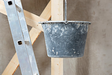 Image showing Dirty bucket and ladder on wall background