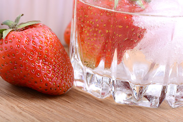 Image showing Strawberry on wooden plate and strawberry frozen with ice in cup