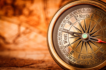 Image showing Vintage compass lies on an ancient world map.