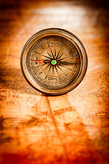 Image showing Vintage compass lies on an ancient world map.