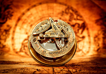 Image showing Vintage compass lies on an ancient world map.