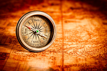 Image showing Vintage compass lies on an ancient world map.