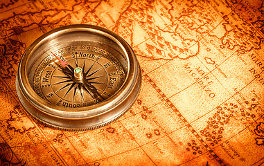 Image showing Vintage compass lies on an ancient world map.