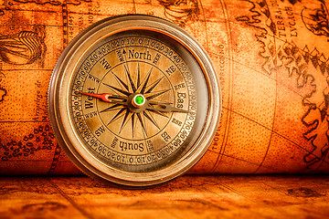 Image showing Vintage compass lies on an ancient world map.