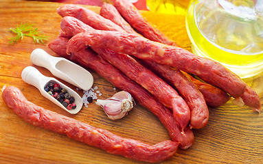 Image showing sausages on the wooden table with aroma spice