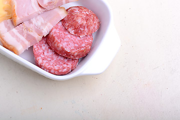 Image showing salami and sausages set on plate on white background