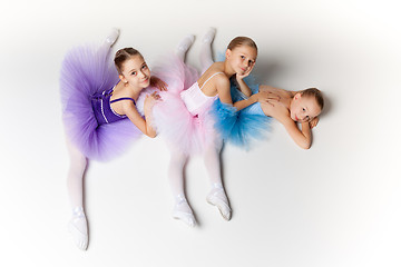 Image showing Three little ballet girls sitting in tutu and posing together
