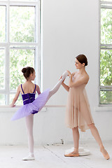 Image showing The little ballerina posing at ballet barre with personal teacher in dance studio