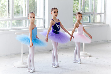 Image showing Three little ballet girls sitting in tutu and posing together