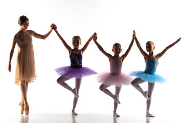 Image showing Three little ballerinas dancing with personal ballet teacher in dance studio