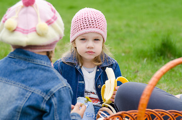 Image showing The sad girl at a picnic eats banana