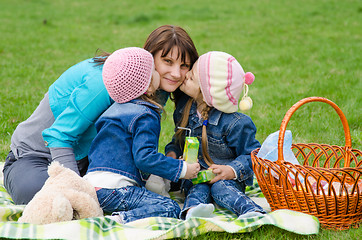 Image showing Two daughters kissing mother while on a picnic