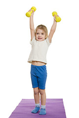 Image showing Four-year-girl lifted dumbbells over a