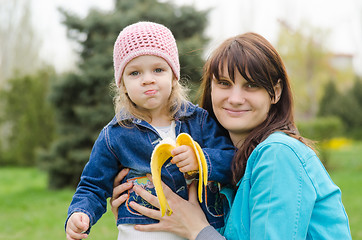 Image showing Mom keeps girl who eats a banana on picnic