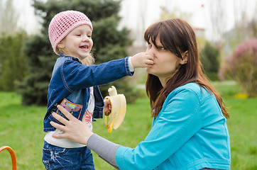 Image showing Girl with banana mother pinched nose