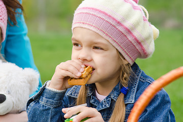 Image showing Girl eating cake at a picnic